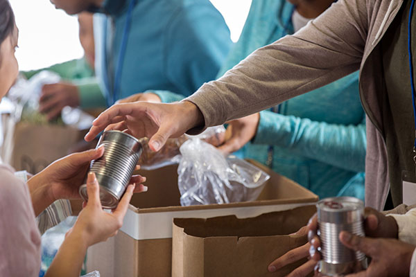 Close up of hands putting food into a box at a community food bank.